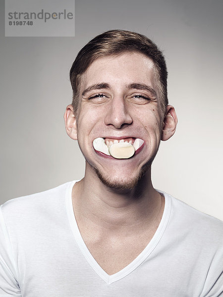 Porträt eines jungen Mannes mit Marshmallow und Süßigkeiten