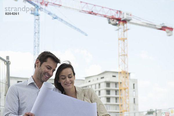 Architekten prüfen Bauplan auf der Baustelle