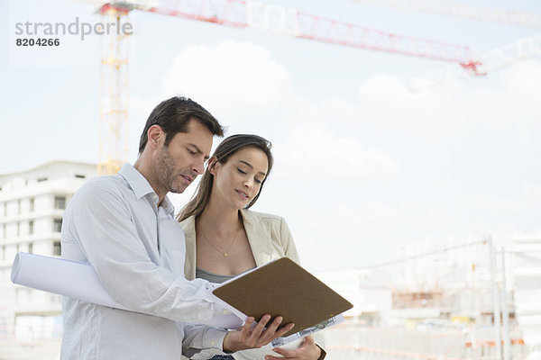 Architekten diskutieren Blaupause auf der Baustelle