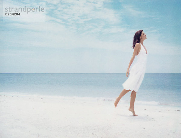 Frau steht auf einem Bein am Strand  Seitenansicht