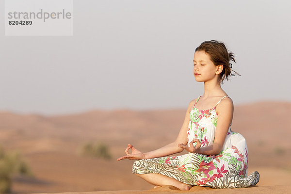 Mädchen meditieren in der Wüste