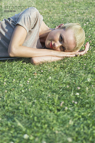 Junge Frau auf Gras liegend  Portrait