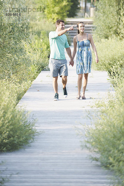 Paar hält sich an den Händen und genießt den Spaziergang entlang der Strandpromenade durch das Naturschutzgebiet.