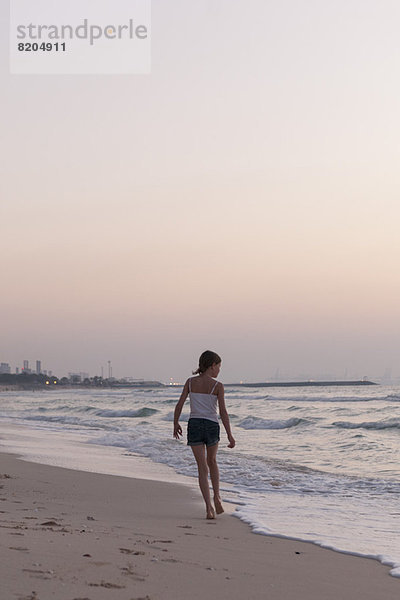 Mädchen am Strand spazieren gehen  auf das Meer schauen