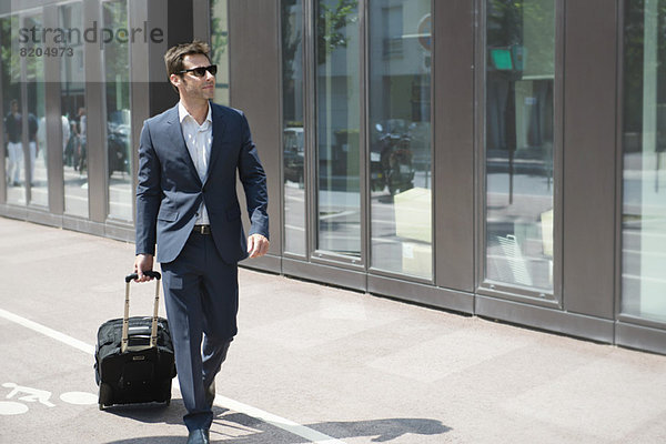 Geschäftsmann mit Sonnenbrille im Gepäck  Spaziergang in der Stadt