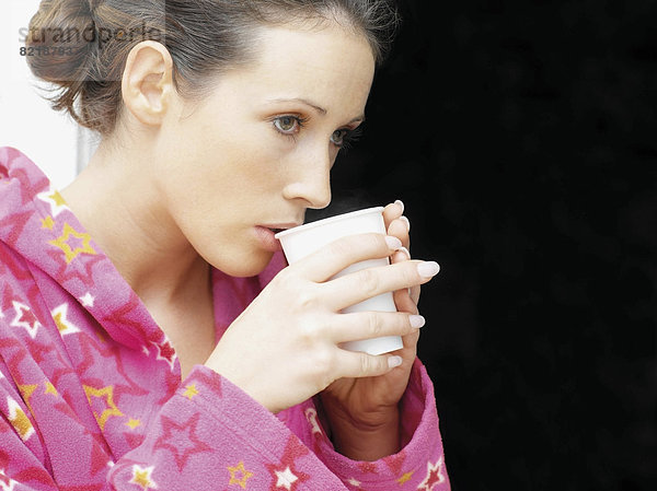 Frau im Morgenmantel trinkt Kaffee
