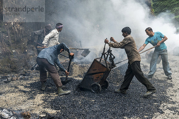 Arbeiter schütten heißen Asphalt auf eine Straße  Straßenbaustelle