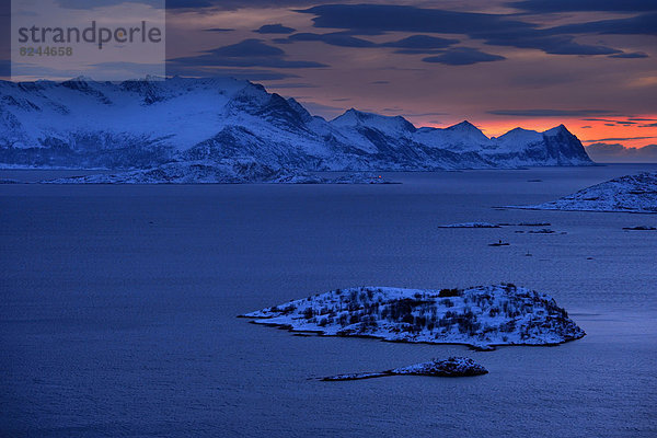 Fjord mit Bergen im Winter zum Sonnenuntergang