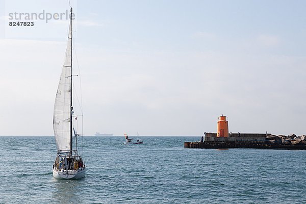 Sailing boat on sea  lighthouse in background