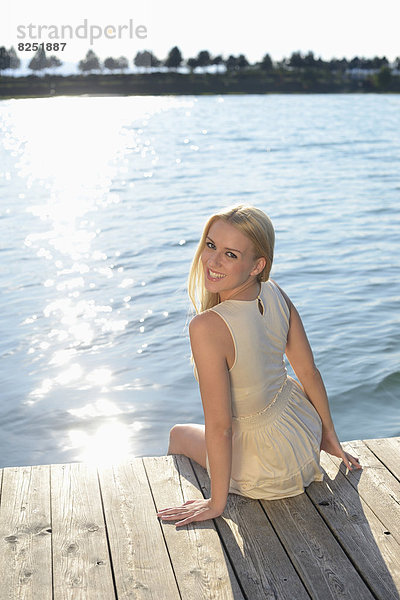 Junge blonde Frau auf einem Steg an einem See  Steiermark  Österreich