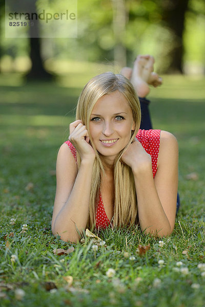 Junge blonde Frau liegt in einem Park