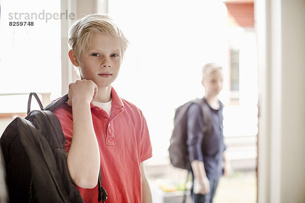 Porträt eines selbstbewussten Jungen mit Rucksack auf dem Weg zur Schule