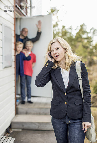 Frau mit Handy und Familie im Hintergrund