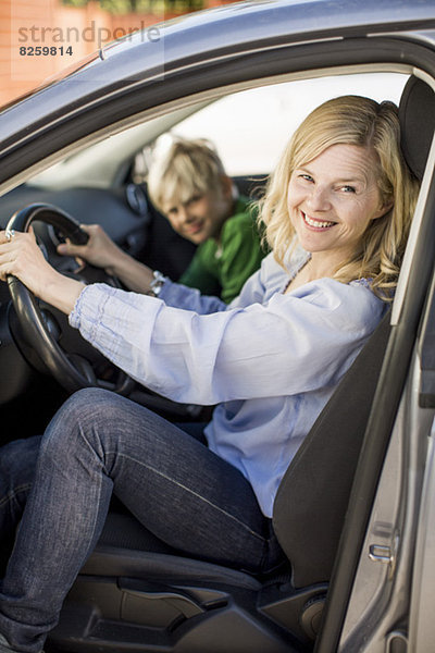 Porträt einer glücklichen Frau beim Autofahren im Sitzen bei einem Sohn