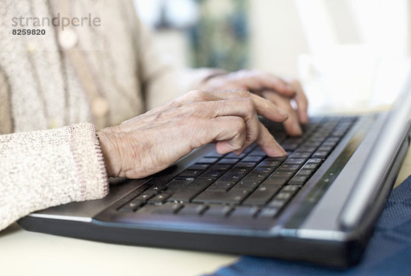 Mittelteil der älteren Frau mit Laptop zu Hause
