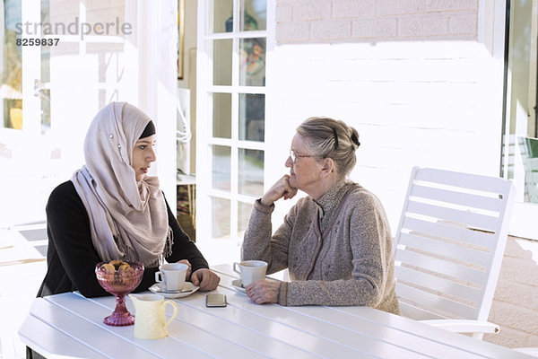 Hausfrau und Seniorin beim Kaffeetrinken auf der Veranda