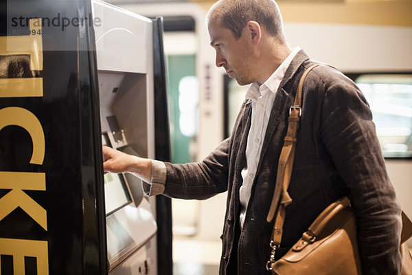 Geschäftsmann mit Fahrkartenautomat am Bahnhof