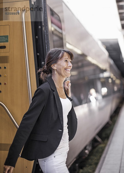 Glückliche Geschäftsfrau beim Aussteigen aus dem Zug