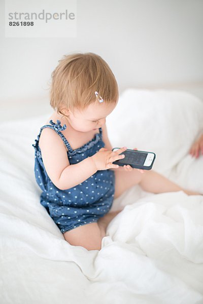 sitzend  benutzen  klein  Telefon  Bett  Mädchen  Handy