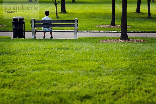 Man sitzt auf Bank im park