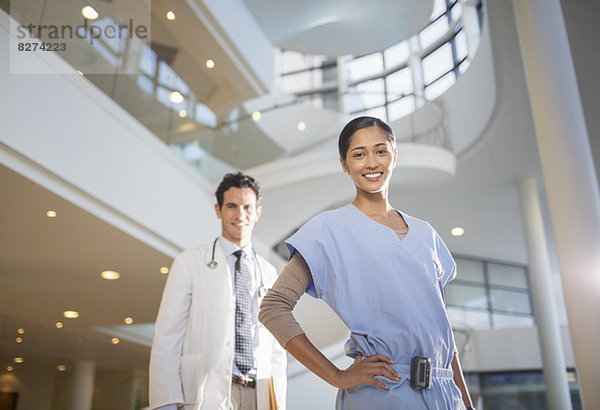 Porträt des lächelnden Arztes und der Krankenschwester im Krankenhausatrium