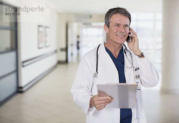 Arzt spricht auf dem Handy im Flur des Krankenhauses
