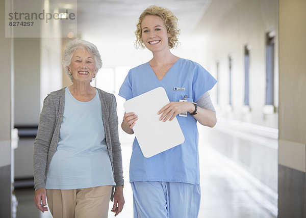 Porträt der lächelnden Krankenschwester und des älteren Patienten im Krankenhausflur