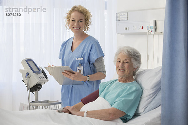 Porträt der lächelnden Krankenschwester und des älteren Patienten im Krankenhauszimmer