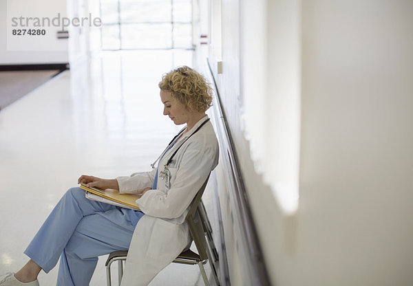 Arzt begutachtet Krankenblatt im Krankenhauskorridor