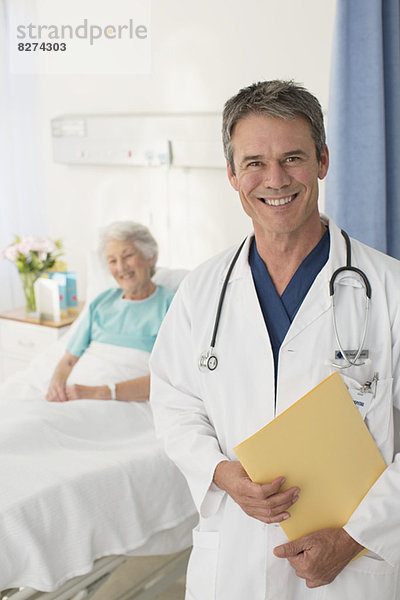 Porträt des lächelnden Arztes mit Patient im Hintergrund
