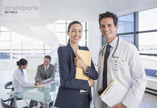 Porträt einer lächelnden Geschäftsfrau und eines Arztes im Meeting
