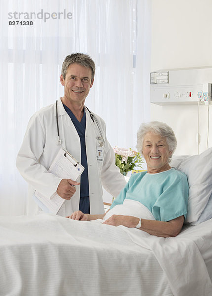 Porträt eines lächelnden Arztes und älteren Patienten im Krankenhauszimmer