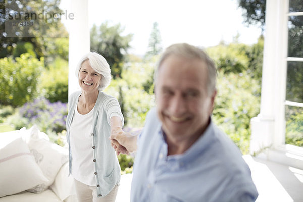 Seniorenpaar hält Hände auf der Terrasse