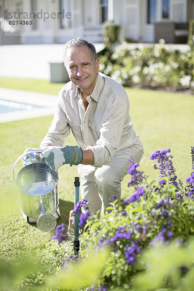 Senior Mann beim Gießen von Pflanzen im Garten