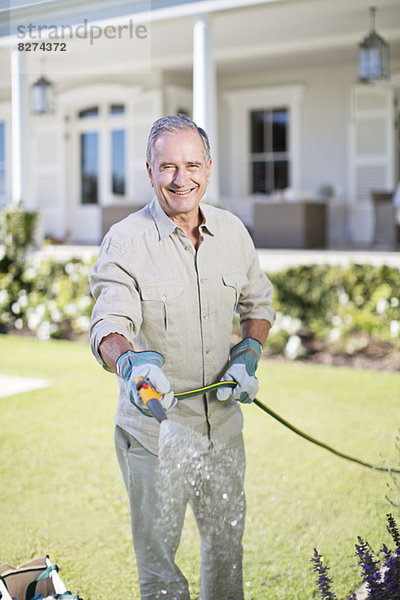 Senior Mann beim Gießen von Pflanzen im Garten