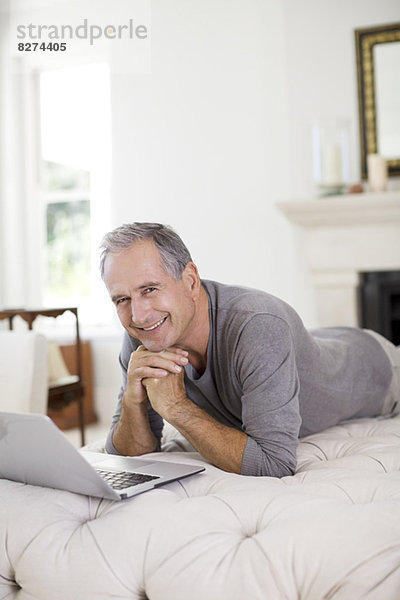 Senior Mann mit Laptop im Wohnzimmer