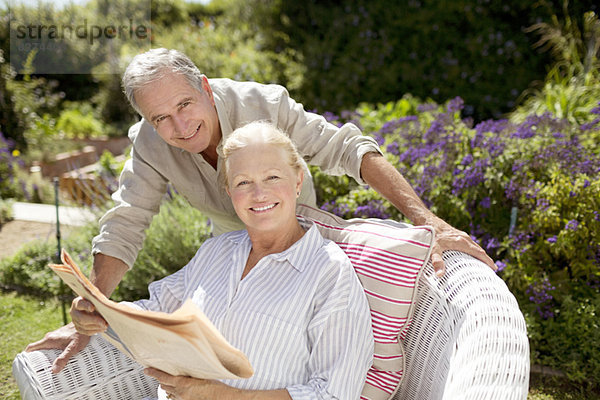 Seniorenpaar beim Zeitungslesen im Garten