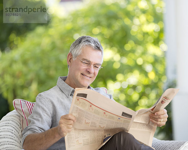 Senior Mann liest Zeitung auf der Terrasse