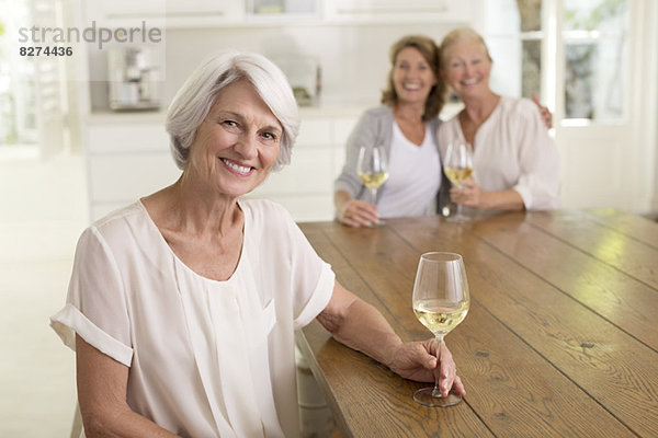 Seniorinnen trinken Weißwein in der Küche