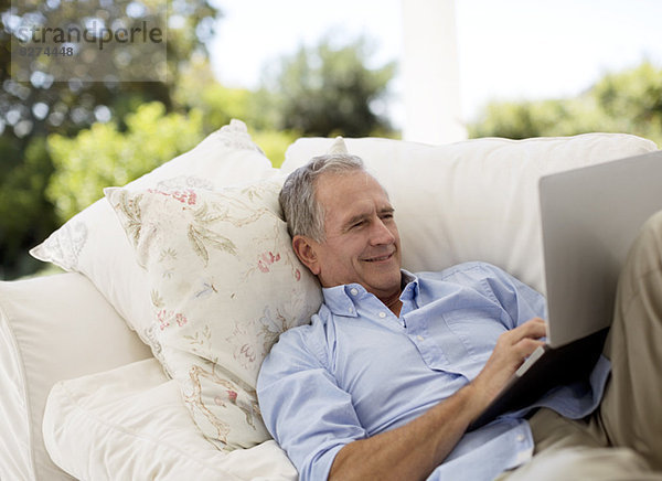 Senior Mann mit Laptop auf der Terrasse Sofa