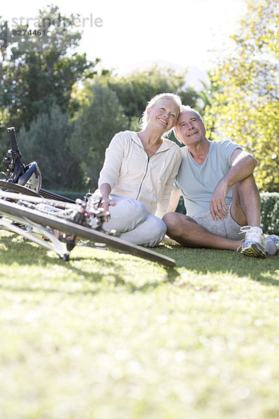 Seniorenpaar sitzend im Park mit Fahrrädern
