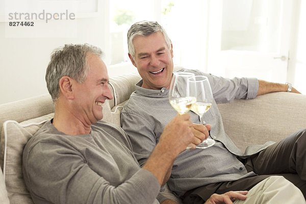 Senior Männer toasten Weingläser auf Sofa