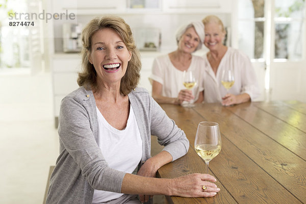 Porträt von lächelnden Seniorinnen beim Weißweintrinken