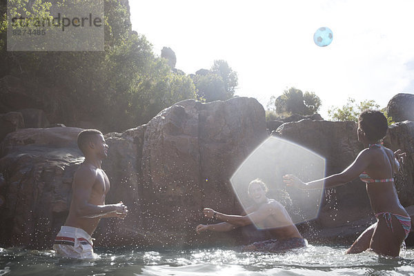 Freunde spielen Fußball im Fluss