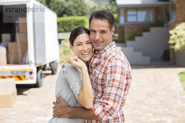 Porträt des lächelnden Paares vor dem neuen Haus
