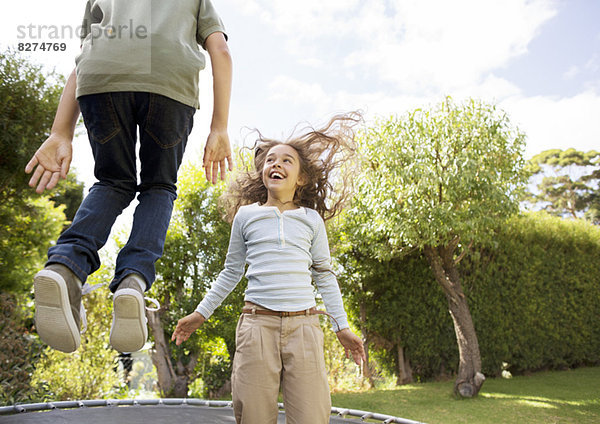 Kinder springen auf Trampolin im Hinterhof