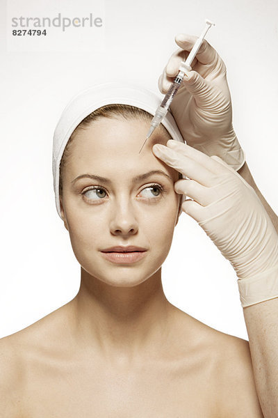 Arzt injiziert Botox in das Gesicht der Frau