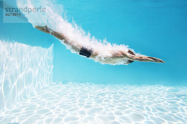 Mann taucht ins Schwimmbad