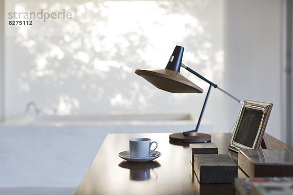 Tasse Kaffee und Lampe auf dem Schreibtisch im Büro