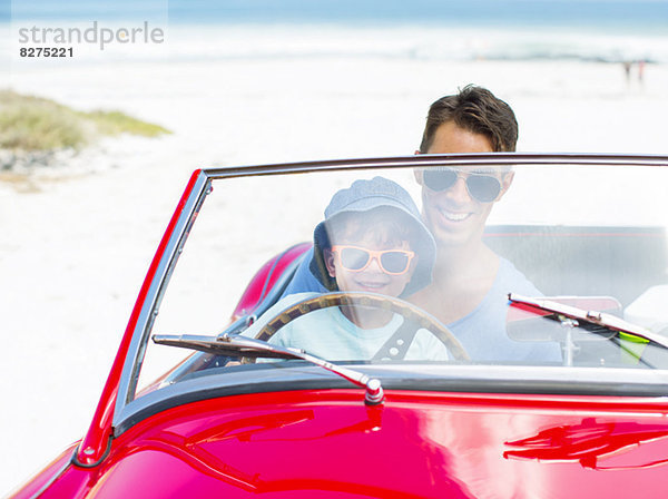 Vater und Sohn fahren Cabrio am Strand